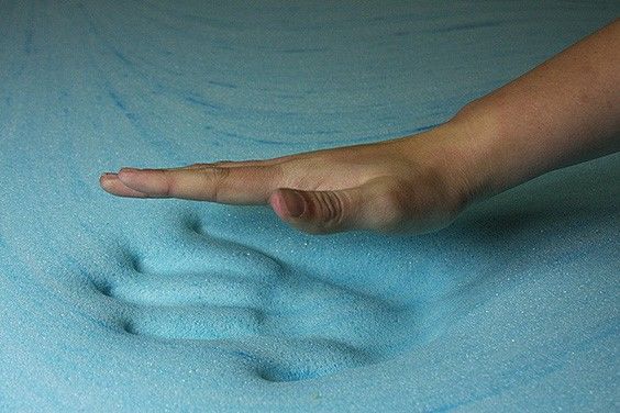 a picture of a hand pressing down a mattress that's blue