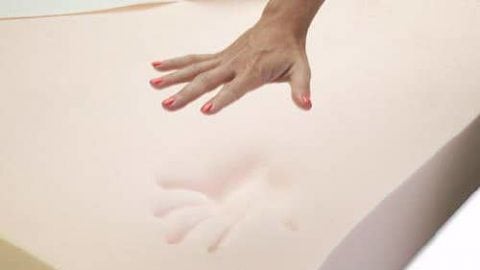 a hand pressing down on a memory foam mattress