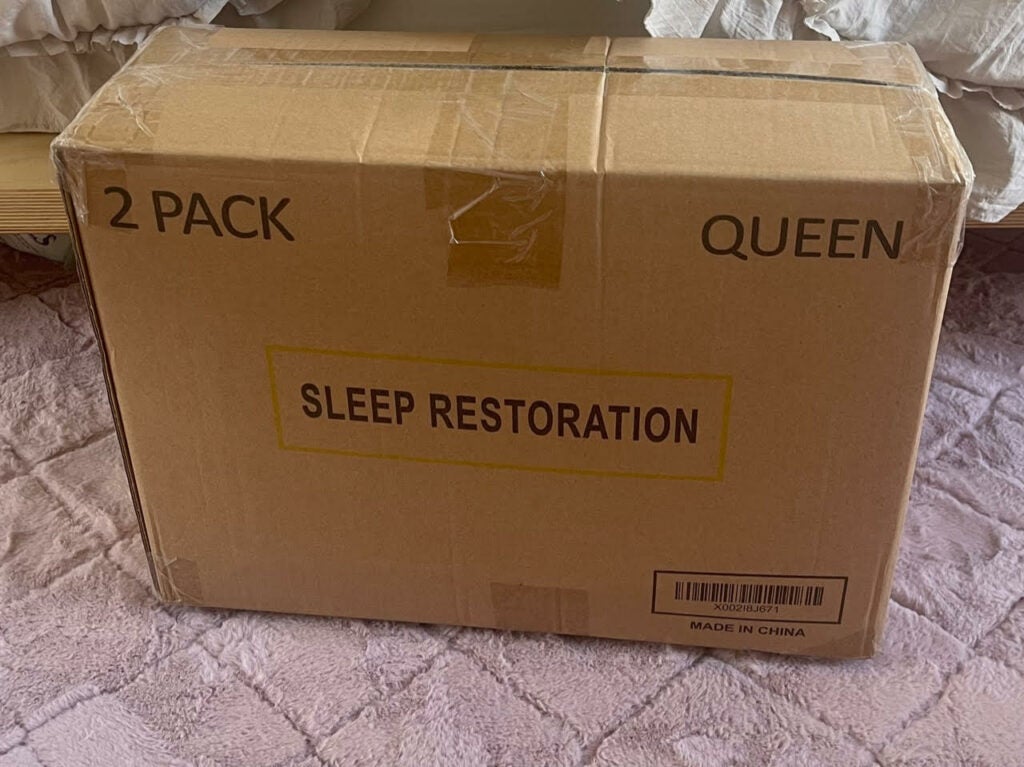 Sleep Restoration pillows in original brown box on a pink rug