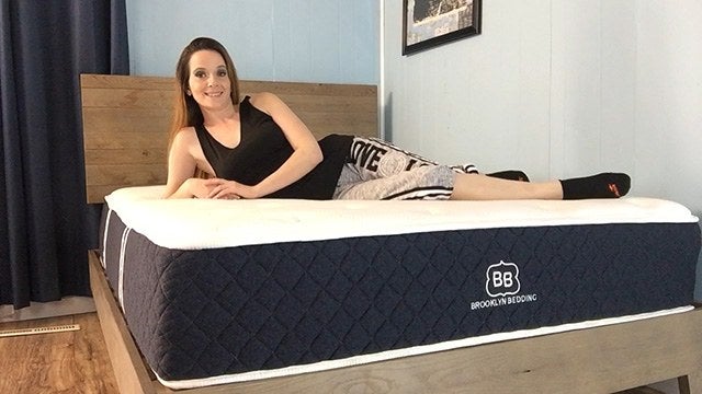 Female posing for camera laying on Brooklyn Bedding mattress
