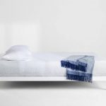 Capser Wave Mattress, hero shot in a white room and a blue blanket laid on the bed
