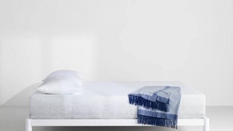 Capser Wave Mattress, hero shot in a white room and a blue blanket laid on the bed