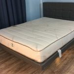 Zenhaven mattress in Jess' base on a bedframe with a wood headrest