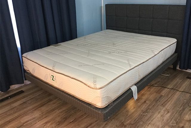 Zenhaven mattress in Jess' base on a bedframe with a wood headrest