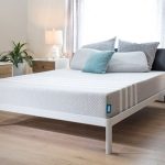 Leesa Mattress image - Leesa gray mattress on a bedframe in a nice lit showroom with tables and drawers