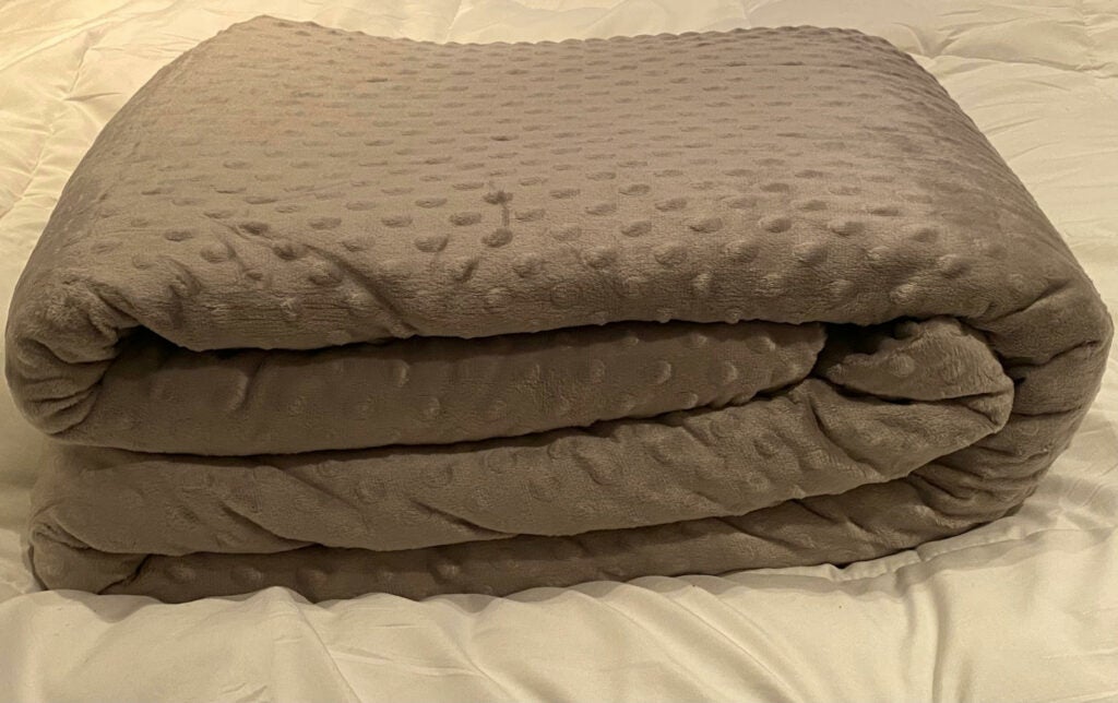 Quility weighted blanket folded on white bed sheets
