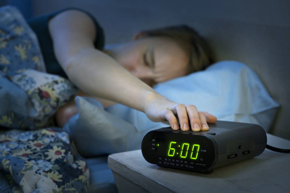 male turning off hitting snooze on digital clock