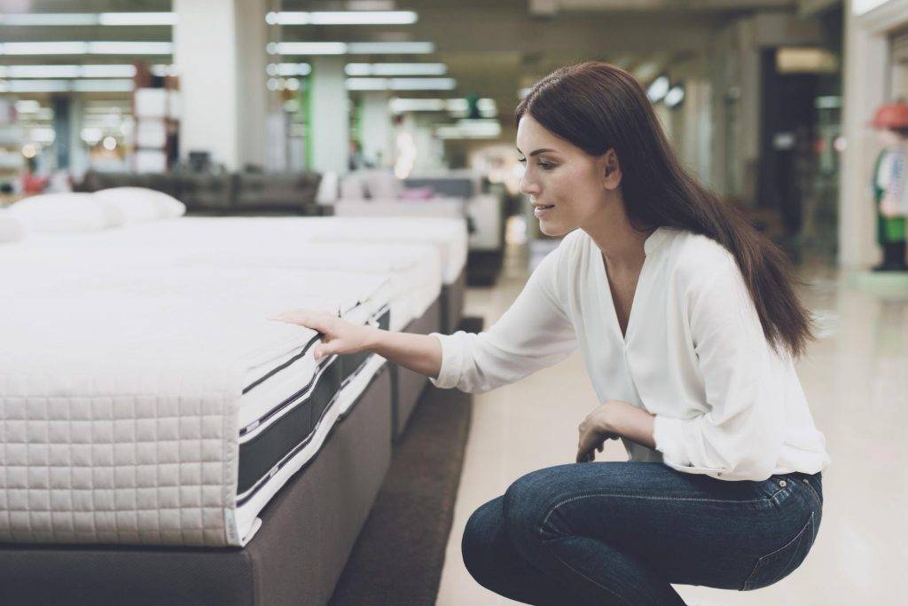 female bending down looking at a mattress