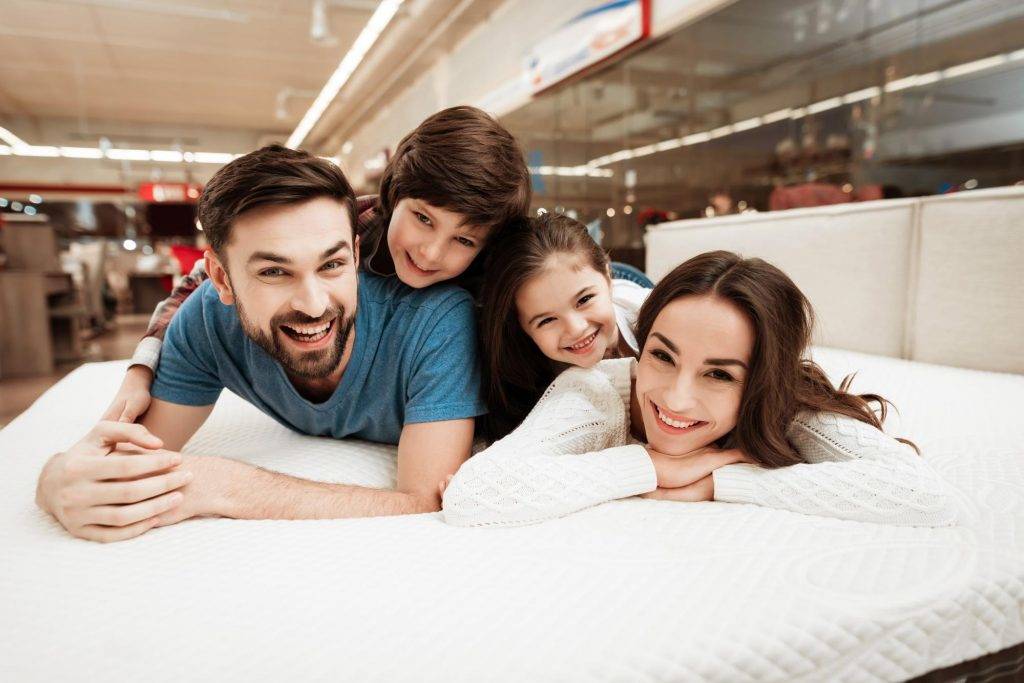 a family of 4 laying on a mattress